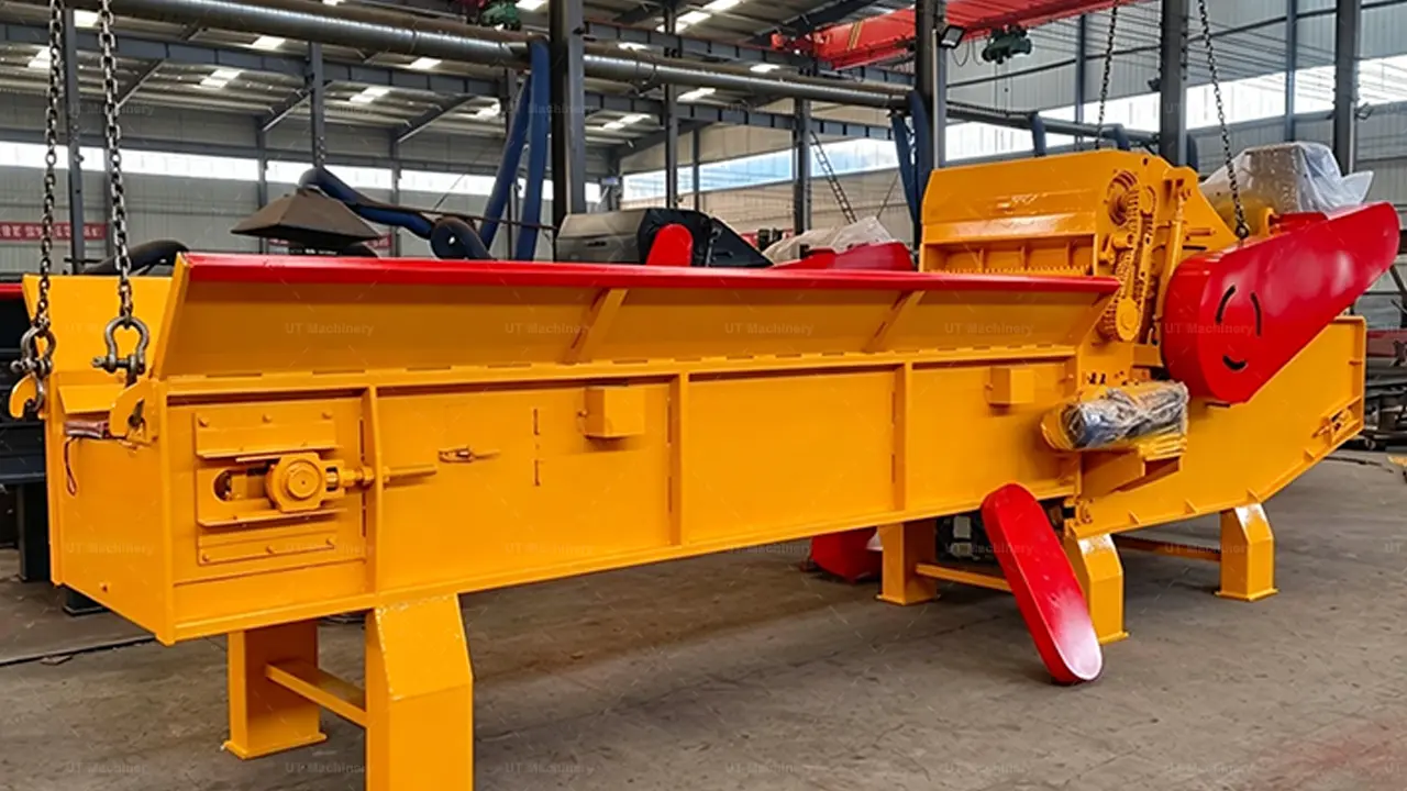 Una potente astilladora de madera industrial con una estructura principal de color amarillo vibrante y llamativos detalles en rojo, lista en la nave de una fábrica. Su robusta unidad de procesamiento, su gran motor y su resistente transportador de cadena y tablillas definen su capacidad de servicio pesado para el astillado de alto volumen.
